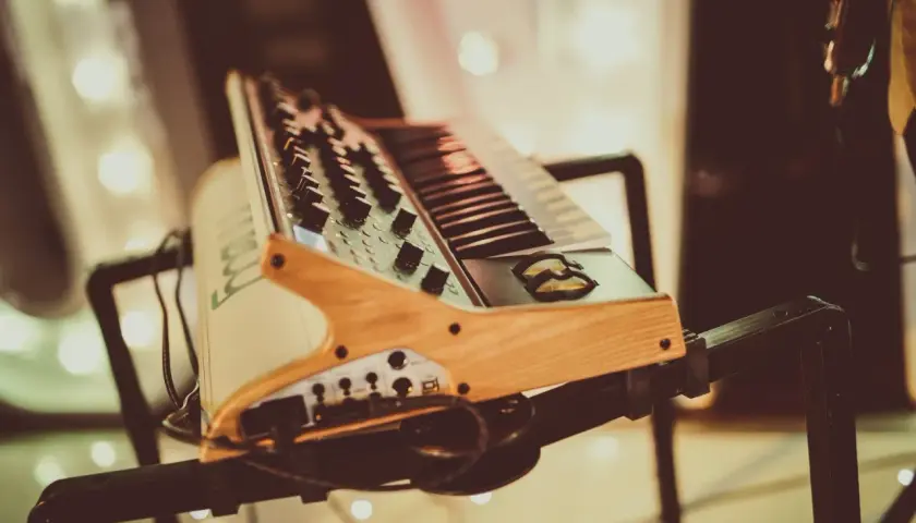 Keyboard muzyczny na czarnym statywie, z drewnianymi elementami.