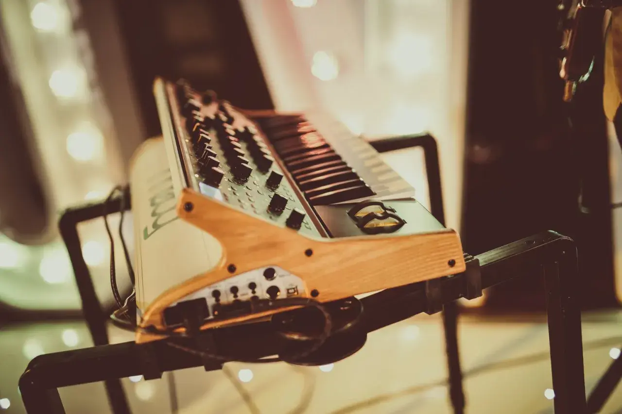 Keyboard muzyczny na czarnym statywie, z drewnianymi elementami.